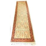 A Persian type runner, with a design of scrolls, flowers, etc., on a cream ground with one wide and