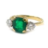 A dress ring, with central square cut green stone, in claw setting, flanked by two round brilliant c