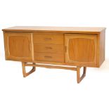 A 1970s teak sideboard, with an arrangement of three drawers, flanked by two panelled doors on shape