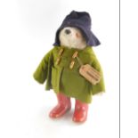 An original Paddington Bear toy, wearing red Dunlop Wellington boots, with green duffel coat, felt h