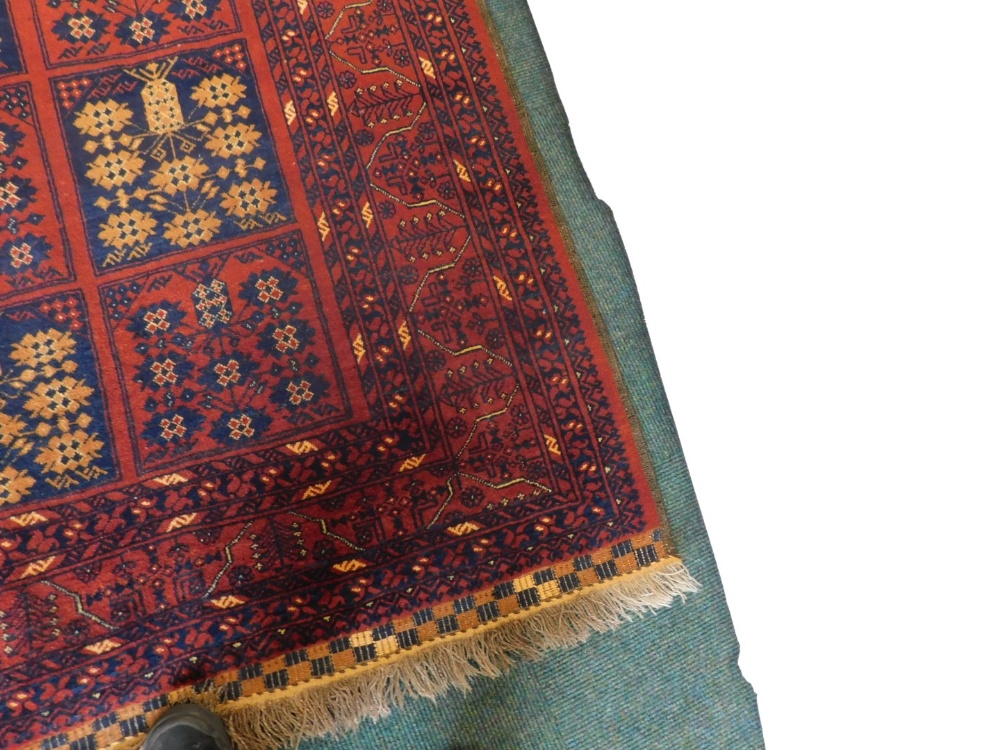 A Balouch type rug, with a design of medallions, in navy and cream on a red ground with multiple bo - Image 2 of 3