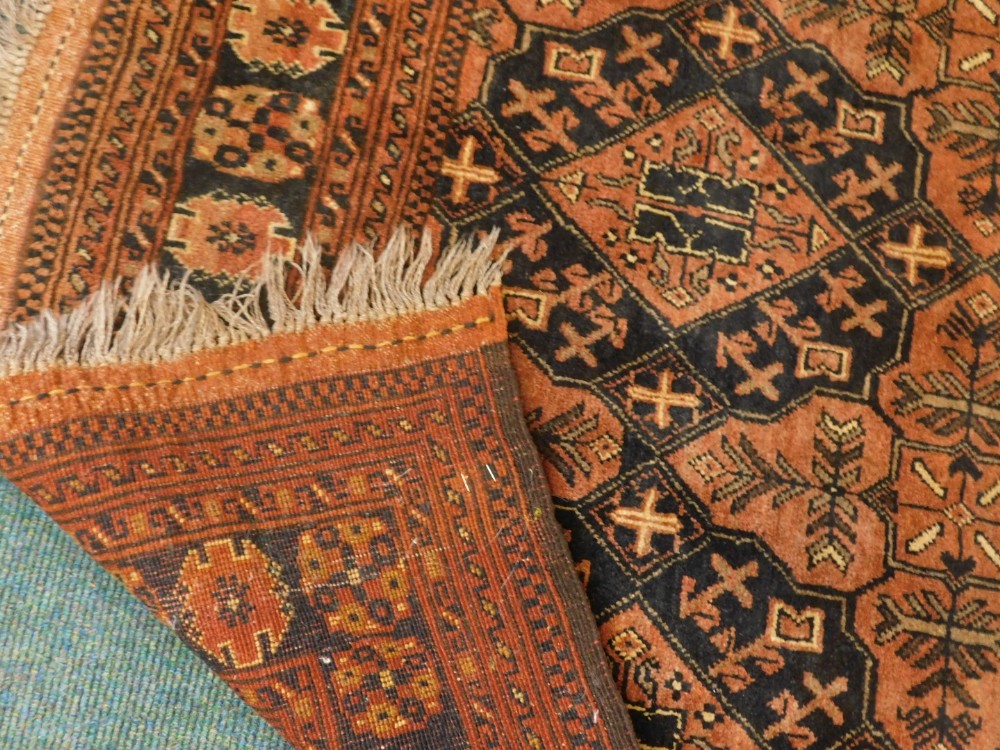 A Balouch type rug, with a design of medallions, in rust coloured medallions on a navy ground with m - Image 3 of 3