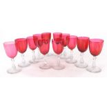 A set of twelve late 19th/early 20thC glasses, each with a cranberry tinted bowl and hollow baluster