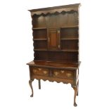 An oak dresser in 18thC style, the top with a raised border above three plate shelves, the base with