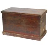 A Victorian stained pine travelling chest, the hinged lid enclosing a vacant interior, on a plinth,