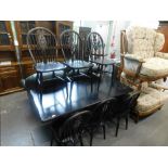 A black painted dining table, and six associated wheel back chairs.