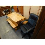 A pine dining table and two associated benches, and an office chair.