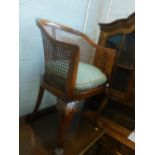 An early 20thC walnut tub shaped chair, with a tub shaped bergere chair, with a caned back on leaf c