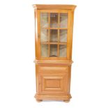 An oak standing corner cabinet, with a single glazed door, above a paneled door, on bun feet, 182cm