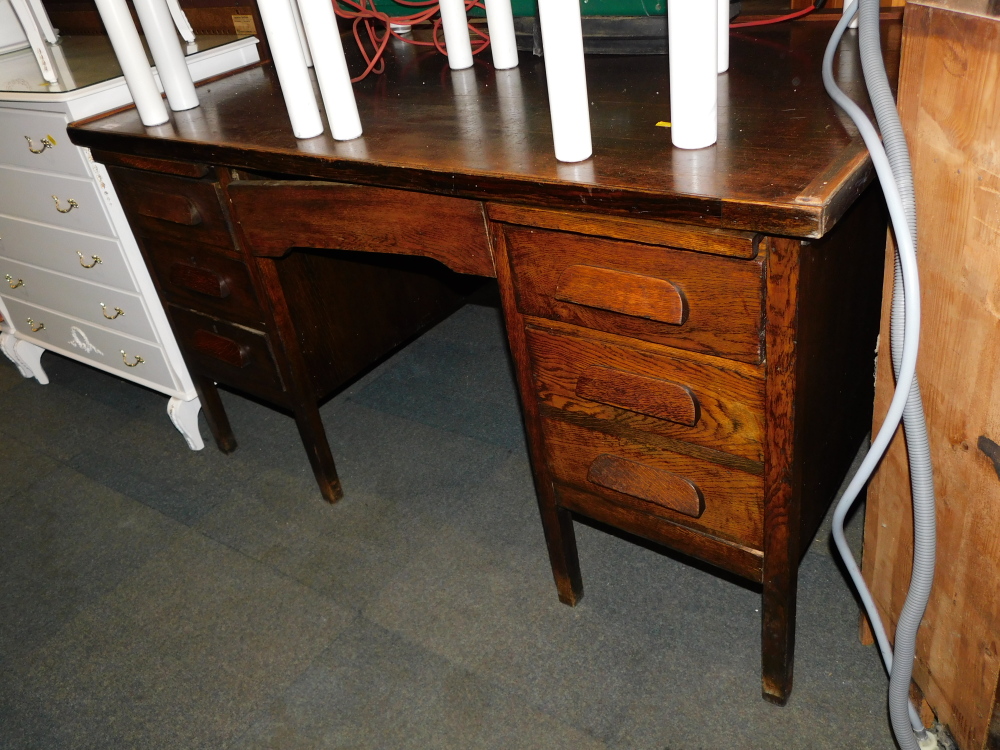 A mid 20thC oak veneered desk, with five drawers raised on block feet.