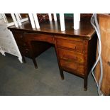 A mid 20thC oak veneered desk, with five drawers raised on block feet.