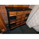 A black and gold painted bank of drawers, with Egyptian style carving.