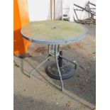 A metal garden table with glass top, together with a cast metal parasol stand. (2)