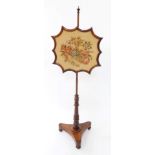 An early Victorian rosewood fire screen, the shaped screen with wool work floral tapestry, raised on