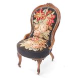 A Victorian rosewood and stump work nursing chair, decorated with roses and lilies, raised on leaf c