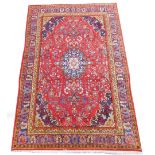 A Sarouk red ground wool rug, decorated with floral motifs, 299cm x 195cm.