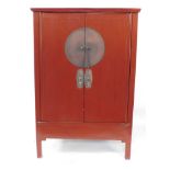 A Chinese 19thC red lacquer marriage cupboard, the out swept pediment over a pair of doors opening t