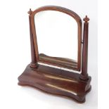 A Victorian mahogany serpentine fronted swing frame toilet mirror, the domed mirror on twin turned s