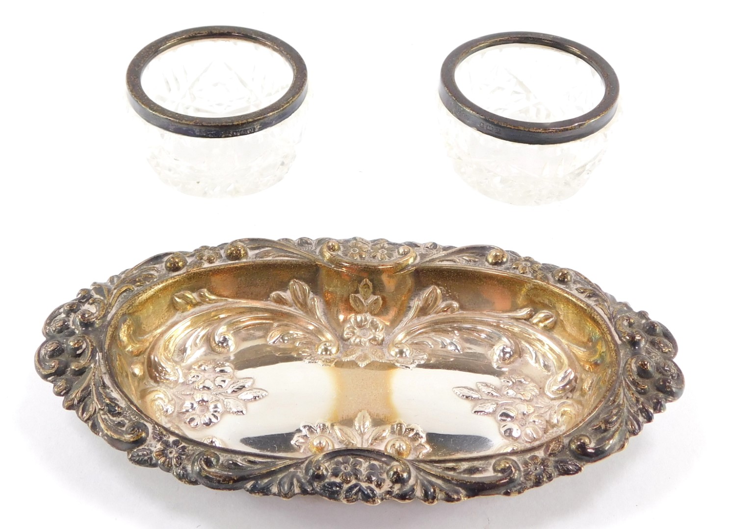 A silver plated pin dish and a pair of cut glass and silver rimmed salts, the plated pin dish with o