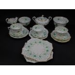 An early 19thC porcelain part tea service, decorated in green and yellow with flowers, within gilt r
