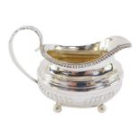 A George III silver cream jug, of semi fluted form, raised on four ball feet, London 1818, 5.6oz.
