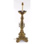 A Victorian Gothic brass alter candlestick, converted to a table lamp, of out swept architectural fo