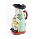 A pearlware early 19thC toby jug, modelled seated holding a jug of frothing stout, 23cm high.