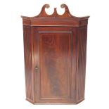 A Georgian style mahogany and boxwood line inlaid hanging corner cupboard, early 20thC, the broken n