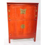 A Chinese red lacquer wedding cabinet, with a pair of doors secured by a lock plate, over two furthe