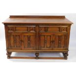 An early 20thC oak sideboard, with two frieze drawers over two pairs of paneled doors, raised on cup