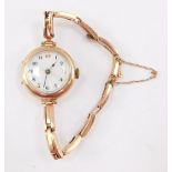 A lady's 9ct rose gold cased wristwatch, circular enamel dial bearing Arabic numerals, on a gold ela