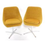A pair of mid century metal framed swivel dining chairs, upholstered in yellow foliate patterned fab