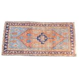 A Caucasian red and blue ground rug, decorated with floral and foliate motifs, within repeating geom