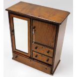 An oak smoker's cabinet, with single glazed door with tobacco cupboard section above three drawers,