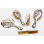 An Edwardian silver backed dressing table set, comprising mirror, hand brush, long brush and a comb,