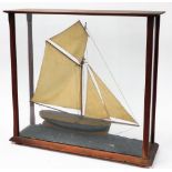 A glazed model yacht, the wooden yacht with four masks and painted in brown and black, mounted in a