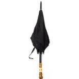 A Victorian parasol, on ebonised handle with brass cap ends, in black material body.