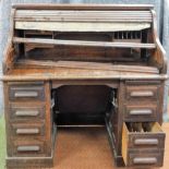 An oak roll top desk, tambour opening to reveal fitted interior above two pedestals, each with four