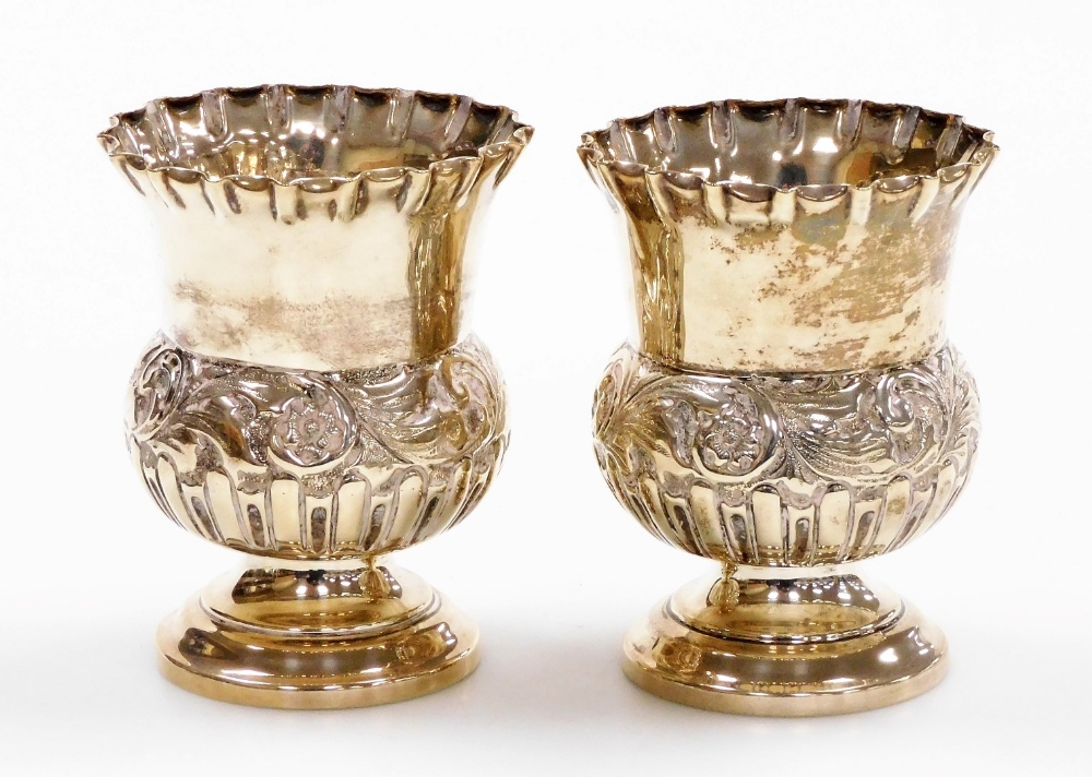 A pair of Edwardian silver thistle shaped vases, with floral crimped borders and embossed flower hea