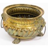 A Dutch brass lion mask bowl, with fluted body and lion mask handles with ring supports, on tripod c