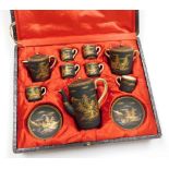 A Japanese cased black ground Satsuma coffee set, decorated in gilt with landscape scenes, marked to