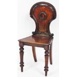 A Victorian mahogany hall chair, with carved shield back with central shield emblem, on tapered legs