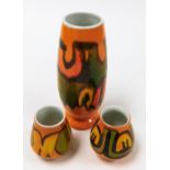 Three Poole vases, in orange ground with yellow and green, 23cm, 8cm, and 10cm high. (3)