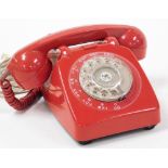 A vintage red telephone, with twist dial.