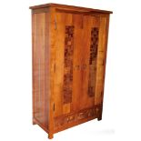 A hardwood double wardrobe, by Acia Wood, the doors with applied panelling and metal swing handles,