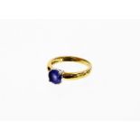 An 18ct gold single stone set dress ring, with a central purple coloured stone in platinum four claw