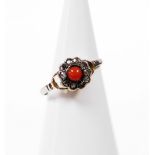 A coral and diamond cluster ring, the central coral surrounded tiny diamonds in a floral setting wit