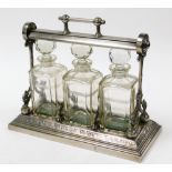 A silver plated Grinsell Patent tantalus, with three cut glass decanters, in case in neoclassical s