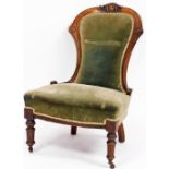 An Edwardian walnut nursing chair, with carved supports upholstered in green draylon, with cream rib