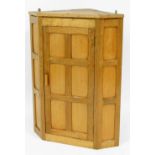 An oak Rabbit Crafts English oak Mouseman style corner cabinet, with panelled oak design opening to
